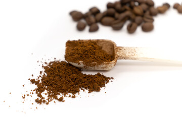 Ground coffee with plastic white spoon and coffee beans isolated on white background.