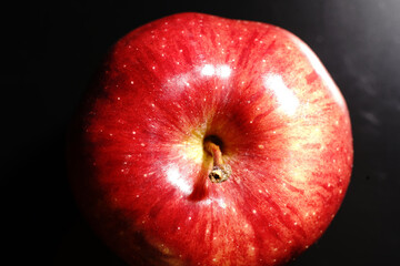 Red Apple on a black background. Half-light and a brightly lit Apple.
