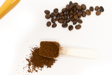 Ground coffee with plastic white spoon and coffee beans isolated on white background. Top view