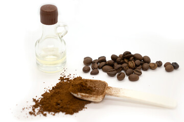 Ground coffee with plastic white spoon, coffee beans and a bottle of vanilla isolated on white background.