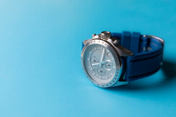 Reloj de pulsera plateado con correa azul sobre fondo azul cielo, con espacio para texto. Accesorios para hombre.