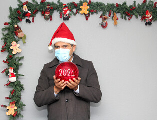 latin man with protection mask, santa claus hat and red sphere,
Christmas decoration, new normal...