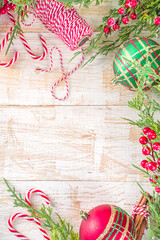 Festive Xmas background with fir tree branches, red winter berries, candy cane decoration and festive gift boxes, top view copy space