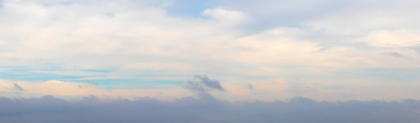 Fototapeta na wymiar Panorama of the sky with a dark cloud below at sunset in soft pastel colors