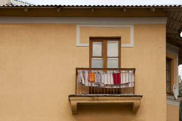 Obraz na płótnie Canvas One balcony in an old yellow apartment block. Linen and towels are dried on the balcony of the house.
