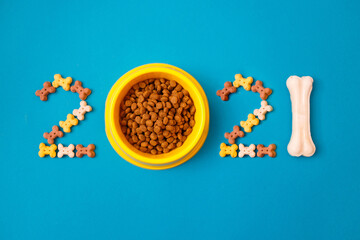 New year greeting card concept. Shape 2021 with doggy accessories on blue background. Canine...