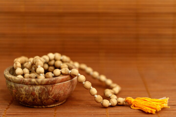 Ceramic bowl with mala beads on wooden background with copy space. Essential accessory for mindfulness or meditation