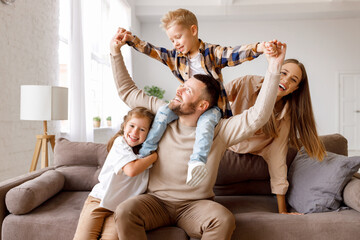 happy family mother father and kids having fun at home on couch .