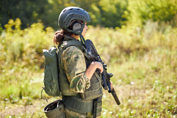 young caucasian military woman holds a gun in her hand in nature, she is going to hunt, hunting in...
