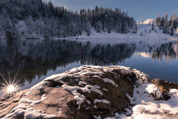 Taubensee im Chiemgau im Winter mit Schnee und Sonne bei blauem Himmel