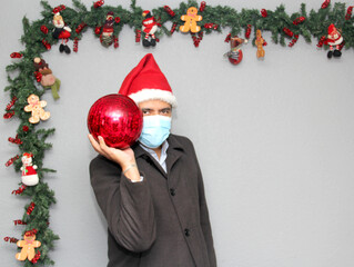latin man with protection mask, santa claus hat and red sphere,
Christmas decoration, new normal...