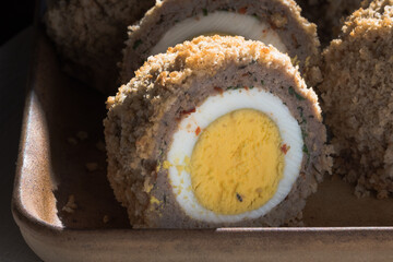 Freshly baked Scottish eggs on a stoneware baking pan. Sausage and eggs.  