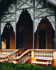 An intricate wooden porch attached to an old yellow building, with Hungarian architectural influence.