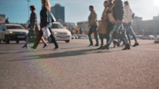 Lens blur, out of focus. A crowd of pedestrians is walking along the street, against the backdrop of a big city. People walk on a sunny day. City life. Slow motion