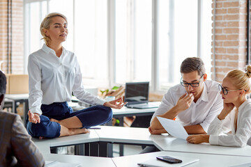 female sits in yoga pose on table at work , meditates alone, keeping calm, need some rest