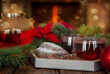 A cup of fruit tea and a stollen against the background of a live fire in the fireplace. Christmas and New Year home holidays concept.