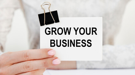 The girl holds a business card with the text GROW YOUR BUSINESS.