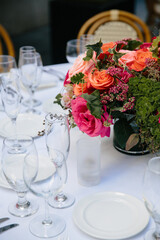 arrangement of pink and orange roses on dinner table with white tablecloth