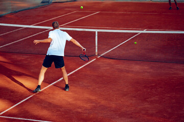 Back view of a man playing tennis on tennis court
