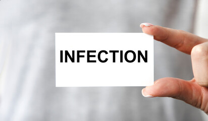The girl holds the text OF INFECTION in front of her.