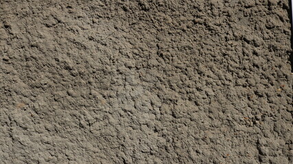 a fragment of an uneven surface of concrete pouring used in construction, a pimpled texture of cement in the foundation of a building