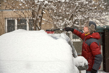 a man brushing the snow off the windshield of his car
