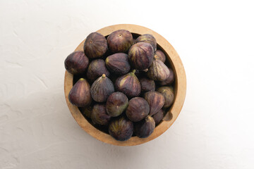 A wooden bowl full of ripe figs