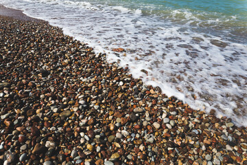 stones on the beach with a wave coming over them