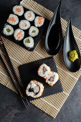 Various kinds of sushi served on black stone plates.