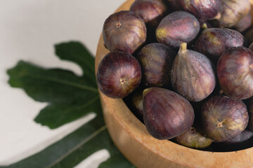 A wooden bowl full of ripe figs