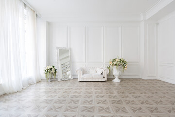 Luxury white interior of living spacious room with elegant chic furniture and high windows.