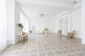 Luxury white interior of living spacious room with elegant chic furniture and high windows.