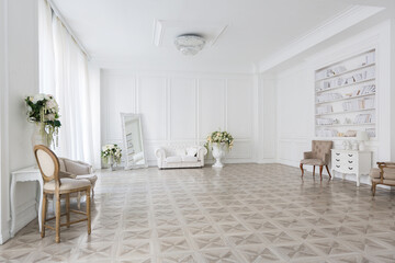 Luxury white interior of living spacious room with elegant chic furniture and high windows.