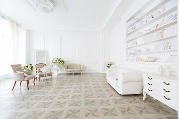 Luxury white interior of living spacious room with elegant chic furniture and high windows.