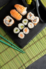 Various kinds of sushi served on black stone plates.