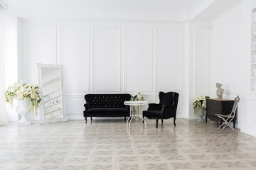 Luxury white interior of living spacious room with elegant chic furniture and high windows.
