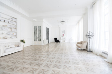 Luxury white interior of living spacious room with elegant chic furniture and high windows.