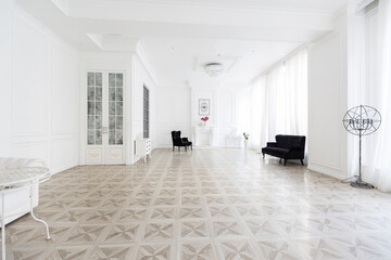 Luxury white interior of living spacious room with elegant chic furniture and high windows.