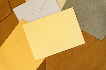 Simple blank of yellow envelope, front view, on background of many colorful envelopes. Concept of post, written correspondence, flat lay