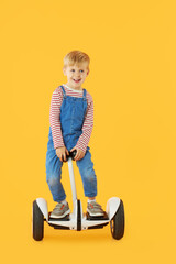 Funny child boy boy riding on hoverboard or gyroscooter on yellow background. Advertising Electrical transport for children