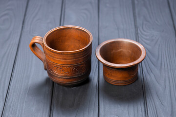 Clay cup and small bowl on black wooden background