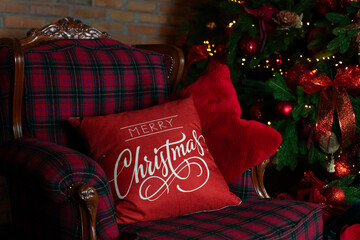 Close up Christmas red pillow on sofa. Decorated living room with a Christmas tree. Interior of...