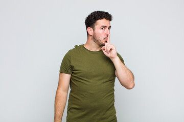 young man asking for silence and quiet, gesturing with finger in front of mouth, saying shh or...