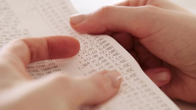 Hands checking grocery receipt or bill after grocery shopping at a supermarket. Expense tracking and home budgeting.
