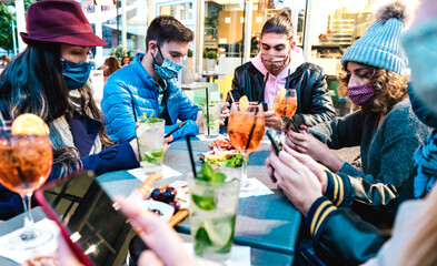 Millenial people using mobile smart phones at cocktail bar - New normal lifestyle concept with friends on contact tracing app during pandemic second wave - Bright filter with focus on central guys