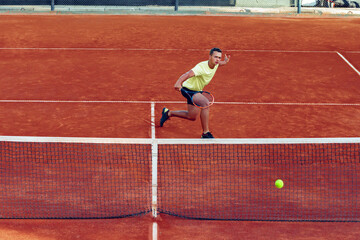 Young handsome man playing tennis on the tennis court