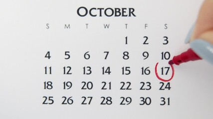 Female hand circle day in calendar date with a red marker. Business Basics Wall Calendar Planner and Organizer. October 17th