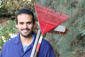Ethnic street cleaner holding broom and rake