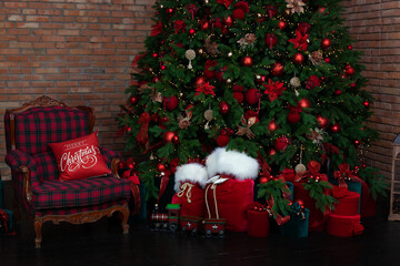 Stylish loft interior of room with Christmas fir tree and checkered armchair. Red sack santa claus...