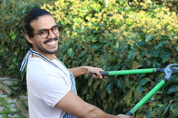 Ethnic man pruning garden manually  
